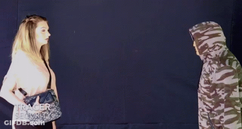 A Woman Spraying A Man With A Purse That Says Tracer Security On It GIF