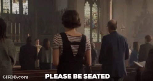 A Woman Standing In A Church With The Words Please Be Seated Written On The Bottom GIF
