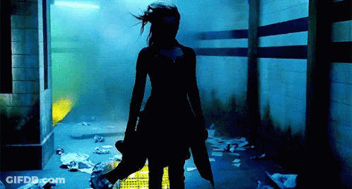 A Woman Standing In A Dark Room Holding A Puppet GIF