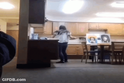 A Woman Standing In A Kitchen With A Painting Of A Woman On The Wall GIF