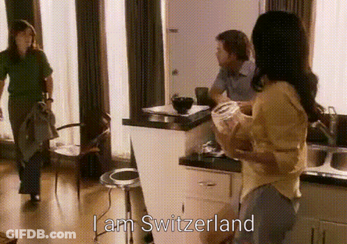 A Woman Standing In A Kitchen With The Words I Am Switzerland Written Above Her GIF