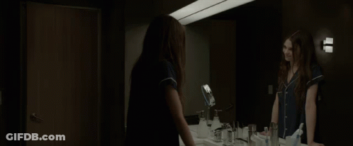A Woman Standing In Front Of A Bathroom Mirror GIF
