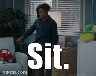 A Woman Standing In Front Of A Couch With The Word Sit On The Bottom GIF