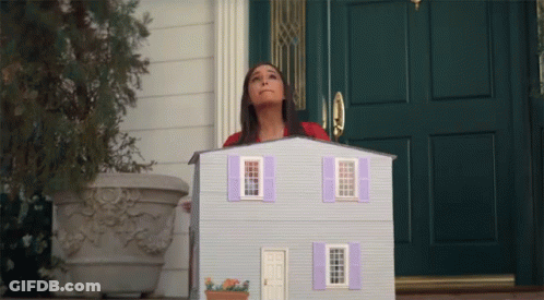 A Woman Standing In Front Of A Doll House GIF
