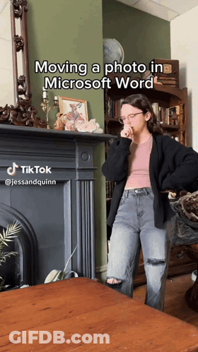 A Woman Standing In Front Of A Fireplace With The Caption Moving A Photo In Microsoft Word On It GIF