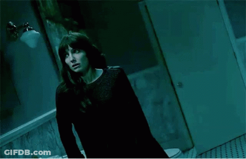 A Woman Standing In Front Of A Mirror In A Dark Room GIF