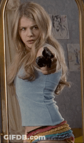 A Woman Standing In Front Of A Mirror Pointing Her Finger At Herself GIF