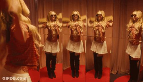 A Woman Standing In Front Of A Mirror Wearing Sunglasses And A Skirt GIF