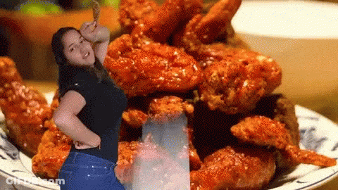 A Woman Standing In Front Of A Plate Of Fried Chicken Wings GIF