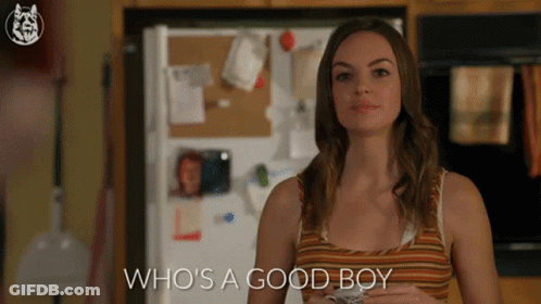 A Woman Standing In Front Of A Refrigerator With The Words Who 'S A Good Boy GIF