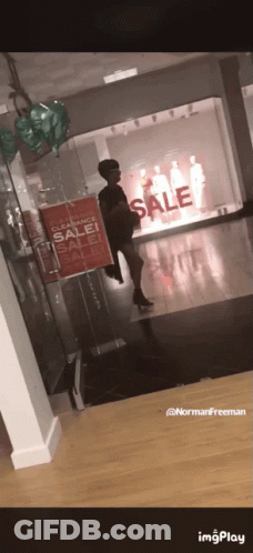 A Woman Standing In Front Of A Store With A Sign That Says Clearance Sale GIF