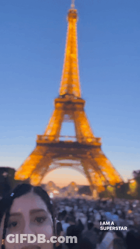 A Woman Standing In Front Of The Eiffel Tower With The Words I Am A Superstar Below Her GIF