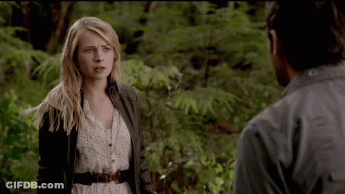 A Woman Standing Next To A Man In A Forest GIF