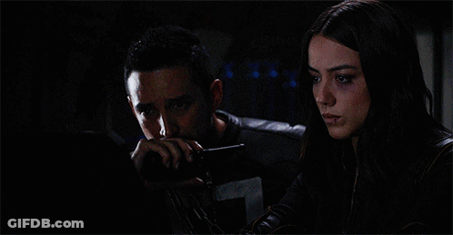 A Woman Standing Next To A Man Laying In A Bed With A Monitor Behind Them That Says A On It GIF