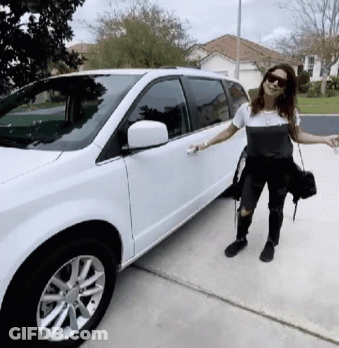 A Woman Standing Next To A White Minivan GIF