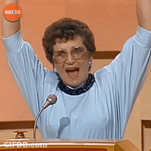 A Woman Stands At A Podium With Her Arms In The Air And A Buzzr Logo Above Her Head GIF