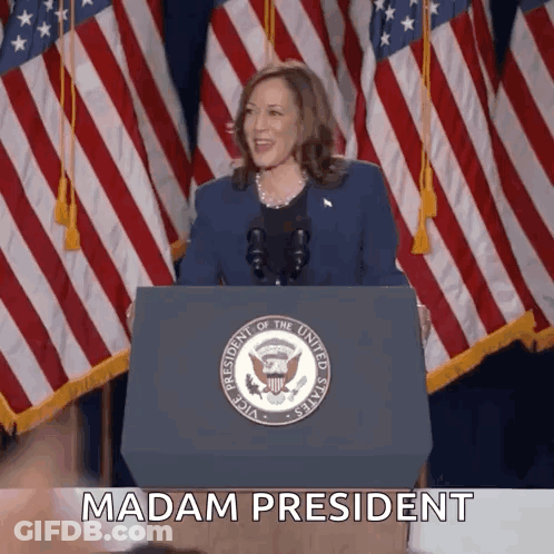 A Woman Stands Behind A Podium With The Words Madam President Written On It GIF