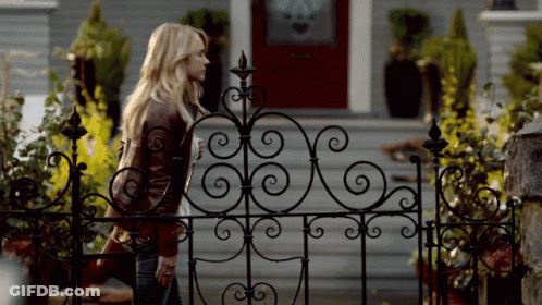 Woman Behind Wrought Iron Fence In Front Of House GIF