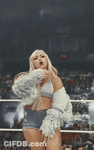 A Woman Stands In A Boxing Ring With The Number 116 On The Wall Behind Her GIF