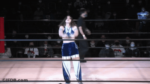 A Woman Stands In A Wrestling Ring With A Referee GIF