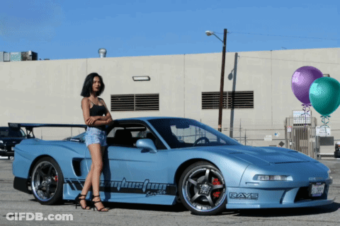 A Woman Stands In Front Of A Blue Car That Says Rays On The Side GIF