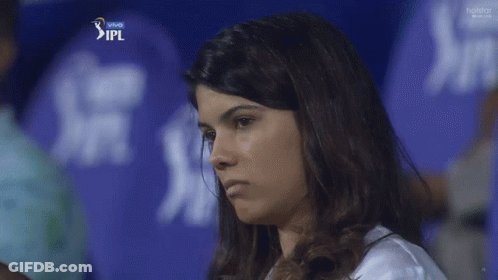 A Woman Stands In Front Of A Blue Ipl Shirt GIF