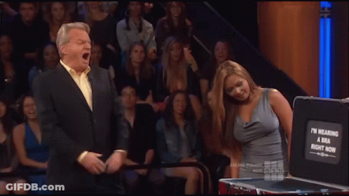 A Woman Stands In Front Of A Briefcase That Says ' I 'M Wearing A Bra Right Now ' On It GIF