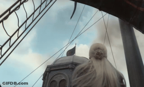 A Woman Stands In Front Of A Building With A Black Flag On Top GIF