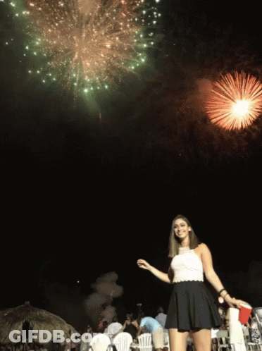A Woman Stands In Front Of A Firework Display GIF