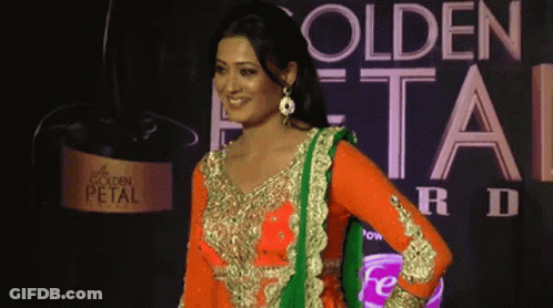 A Woman Stands In Front Of A Golden Petal Advertisement GIF