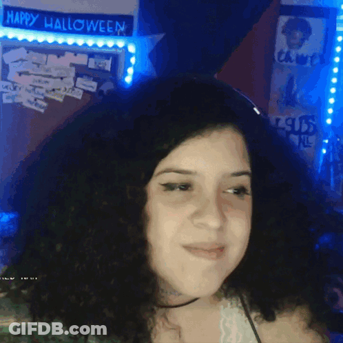 A Woman Stands In Front Of A Happy Halloween Sign GIF