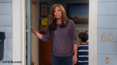 A Woman Stands In Front Of A House With The Number 60 On The Side GIF