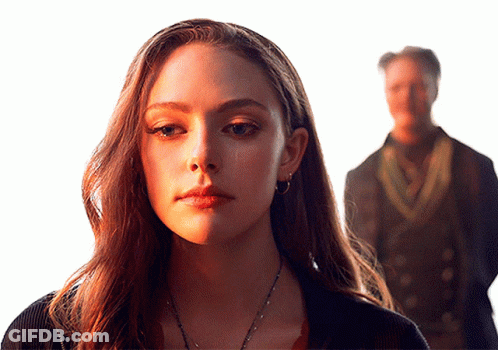 A Woman Stands In Front Of A Man In A Dark Suit GIF