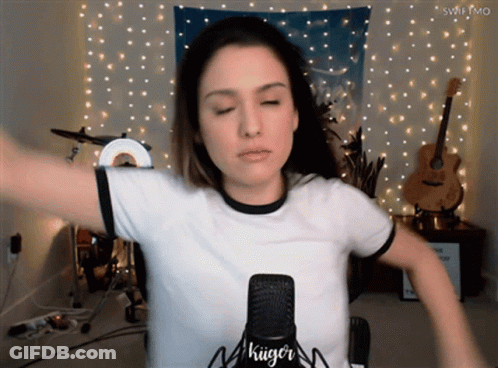 A Woman Stands In Front Of A Microphone That Says " Kiiger " On It GIF