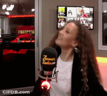 A Woman Stands In Front Of A Microphone That Says Zoomer Radio.com GIF