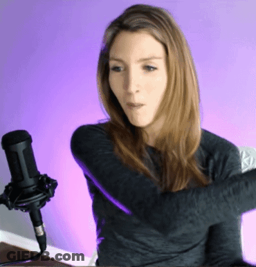 A Woman Stands In Front Of A Microphone With Her Arms Crossed GIF