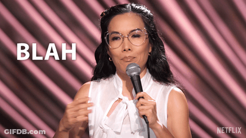 A Woman Stands In Front Of A Microphone With The Word Blah Behind Her GIF