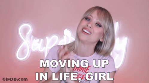 A Woman Stands In Front Of A Neon Sign That Says Moving Up In Life Girl GIF