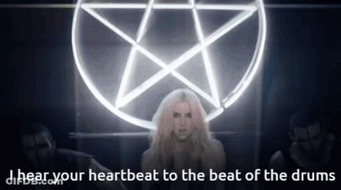 A Woman Stands In Front Of A Pentagram With The Words I Hear Your Heartbeat To The Beat Of The Drums GIF