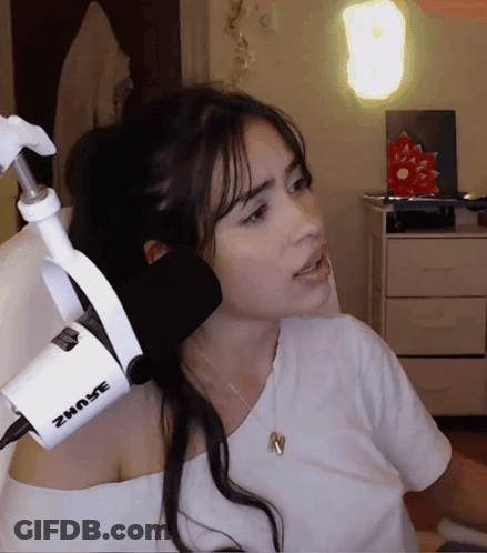 A Woman Stands In Front Of A Shure Microphone While Wearing A White Shirt GIF