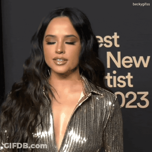 A Woman Stands In Front Of A Sign That Says " Best New Tist " GIF