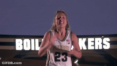 A Woman Stands In Front Of A Sign That Says ' Boilermakers ' On It GIF