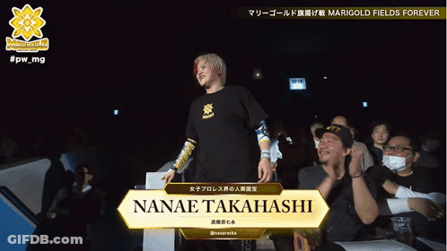 A Woman Stands In Front Of A Sign That Says Nanae Takahashi GIF