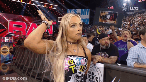 A Woman Stands In Front Of A Sign That Says Raw On It GIF