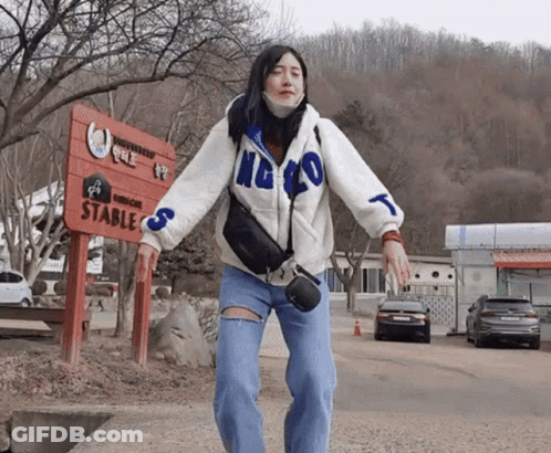 A Woman Stands In Front Of A Sign That Says Stables GIF