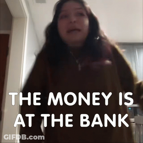 A Woman Stands In Front Of A Sign That Says " The Money Is At The Bank " GIF