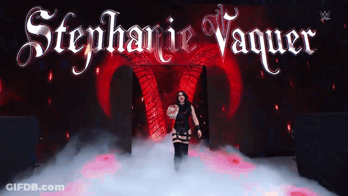 A Woman Stands In Front Of A Stage With The Name Stephanie Vaquer Written On It GIF