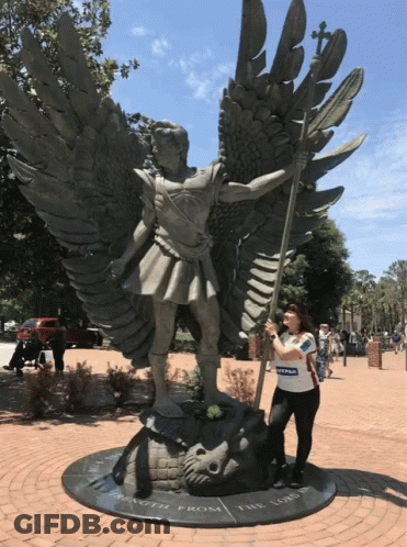 A Woman Stands In Front Of A Statue That Says Strength From The Lord On It GIF