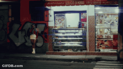 A Woman Stands In Front Of A Store That Says Antojate GIF