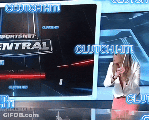 A Woman Stands In Front Of A Television Screen That Says Clutch Hit GIF